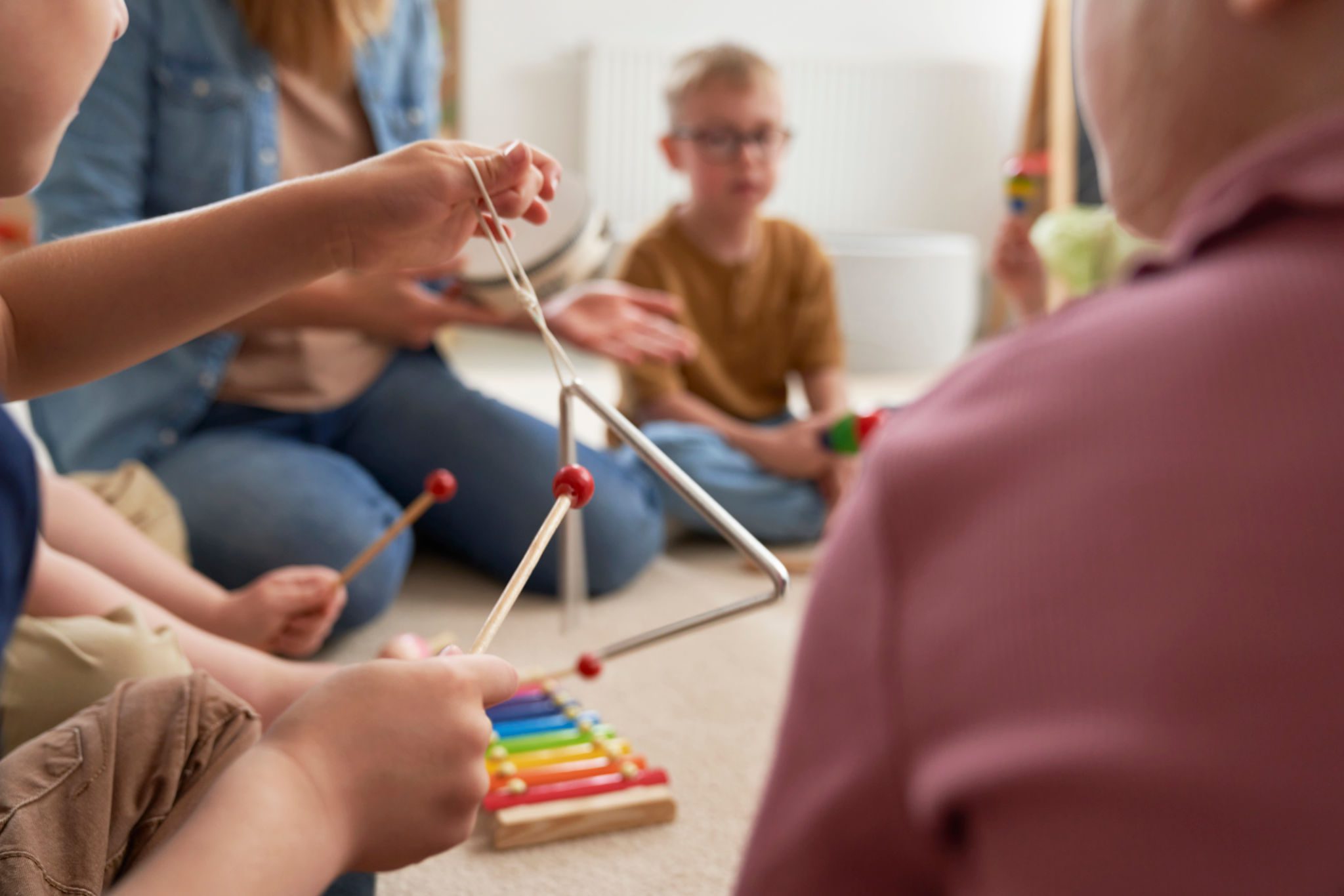 Children playing musical instruments together on floor.
